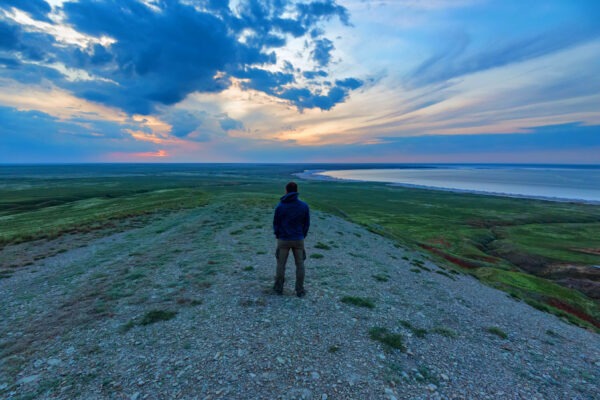 Traveler is standing on the sea shore and looks at horizon