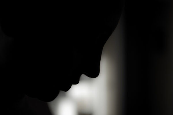 A profile of a woman emerges from the darkness.