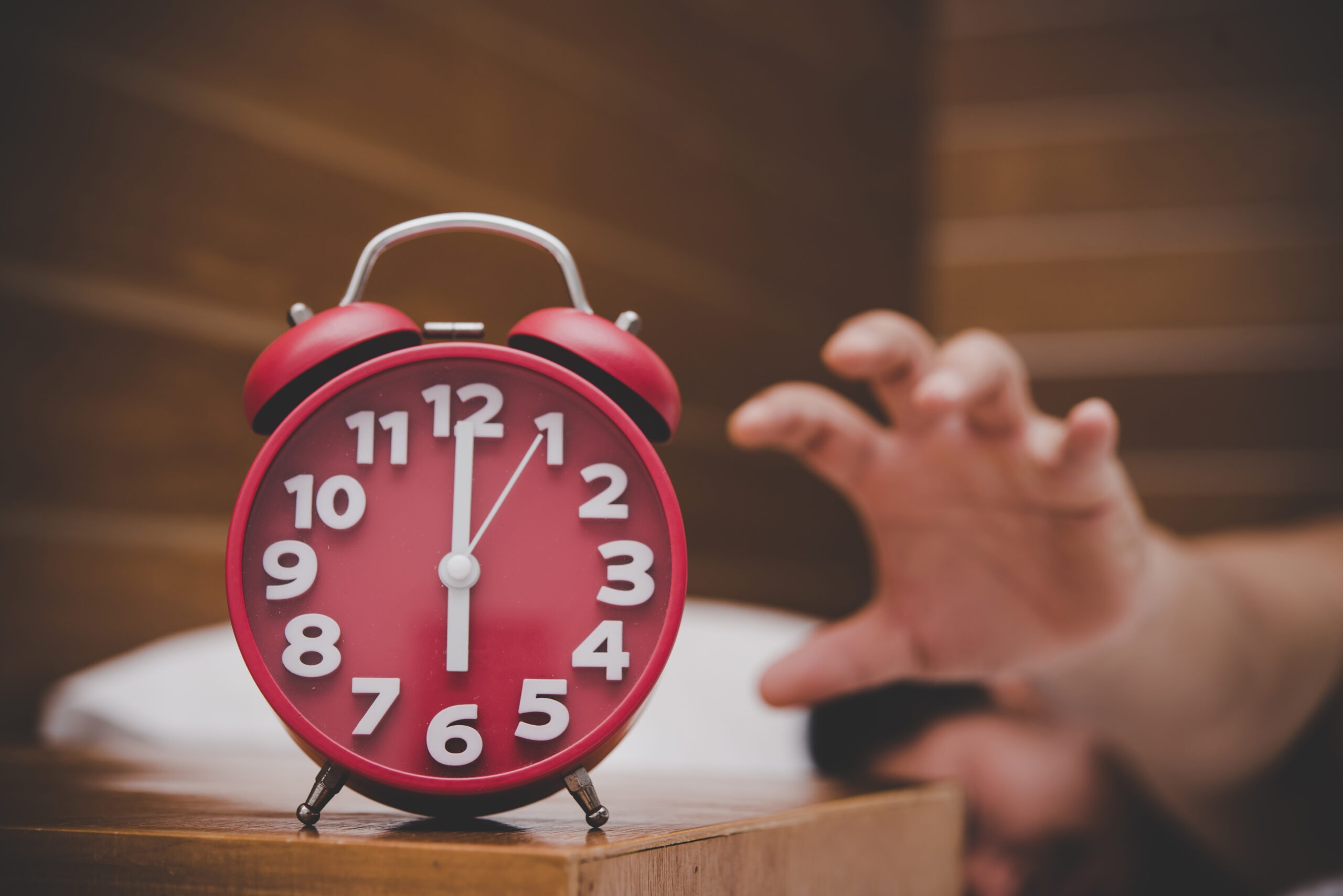 Man being awakened by an alarm clock in his bedroom.