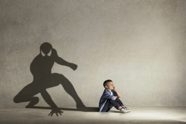 Conceptual image with boy and shadow of fit athlete on the studio wall