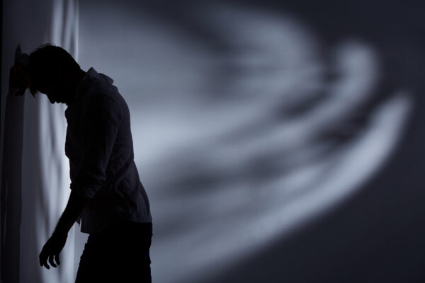 Depressed and broken man standing alone close to the wall