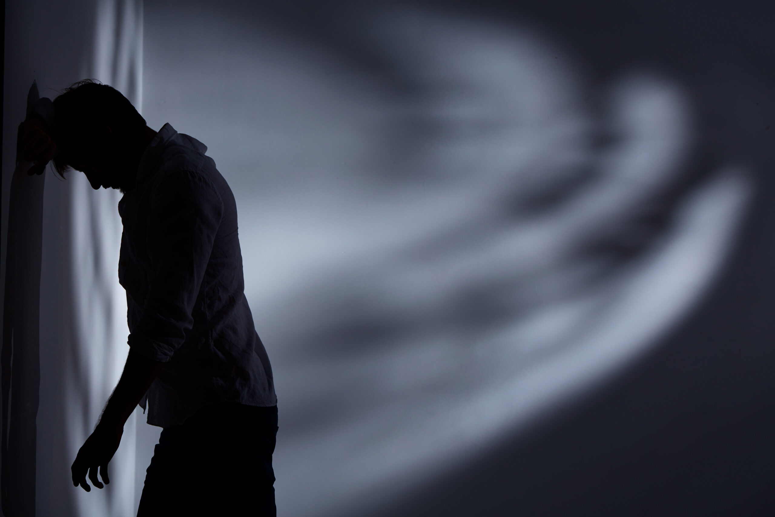 Depressed and broken man standing alone close to the wall