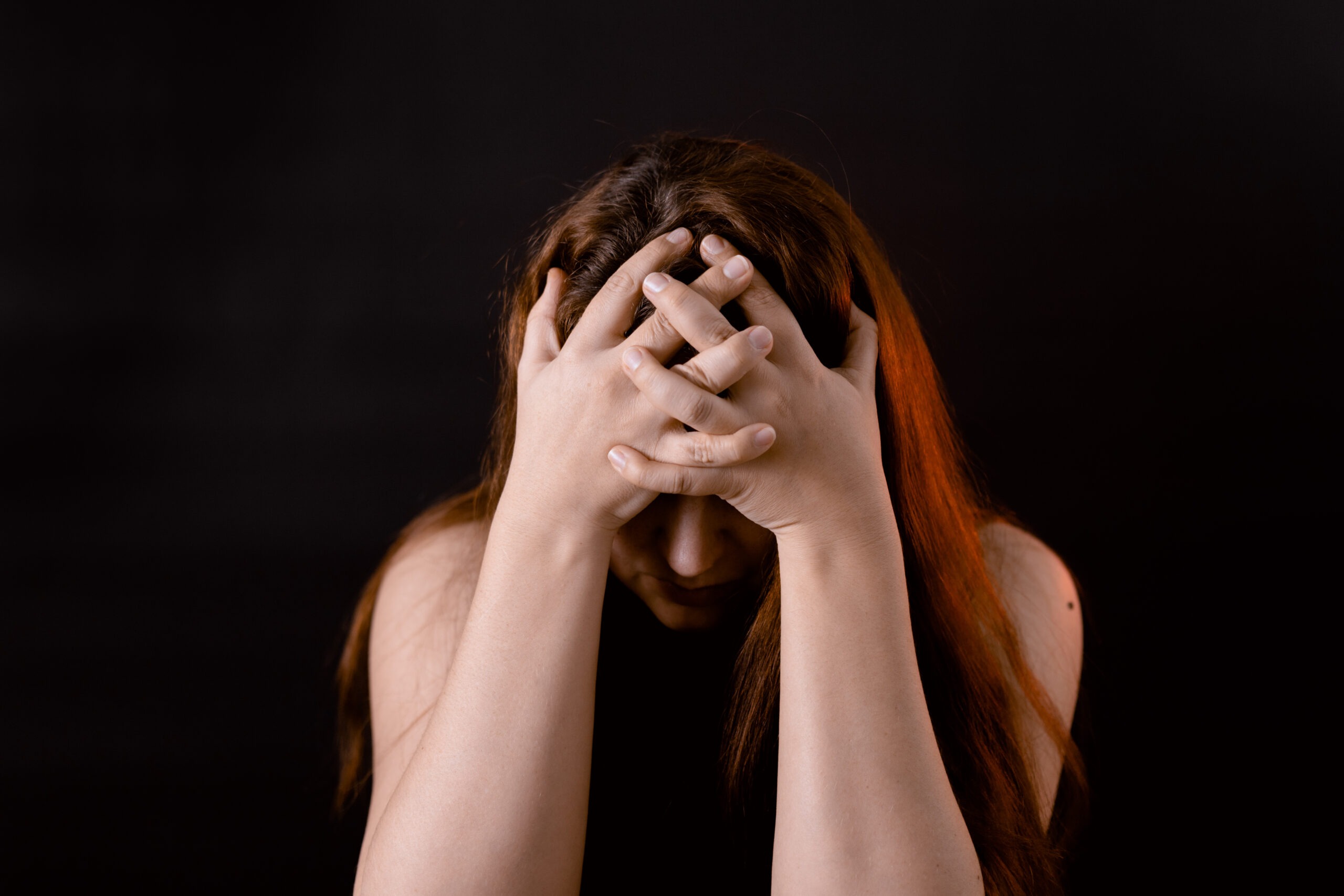Woman putting her head down covering face with hands.